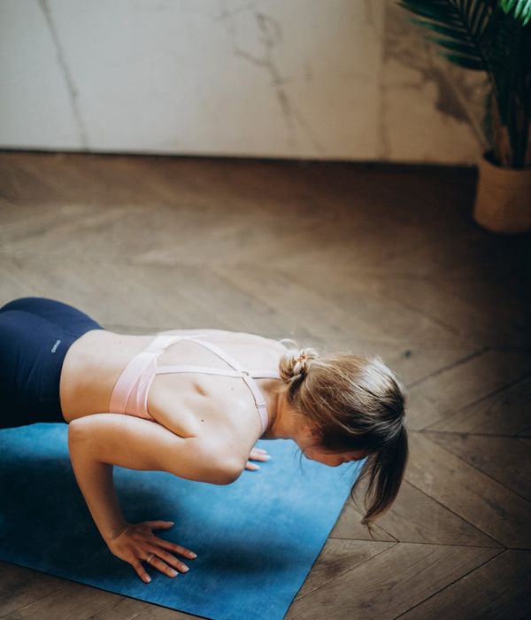 Woman in a calm, mindful stretching pose in a softly lit room.